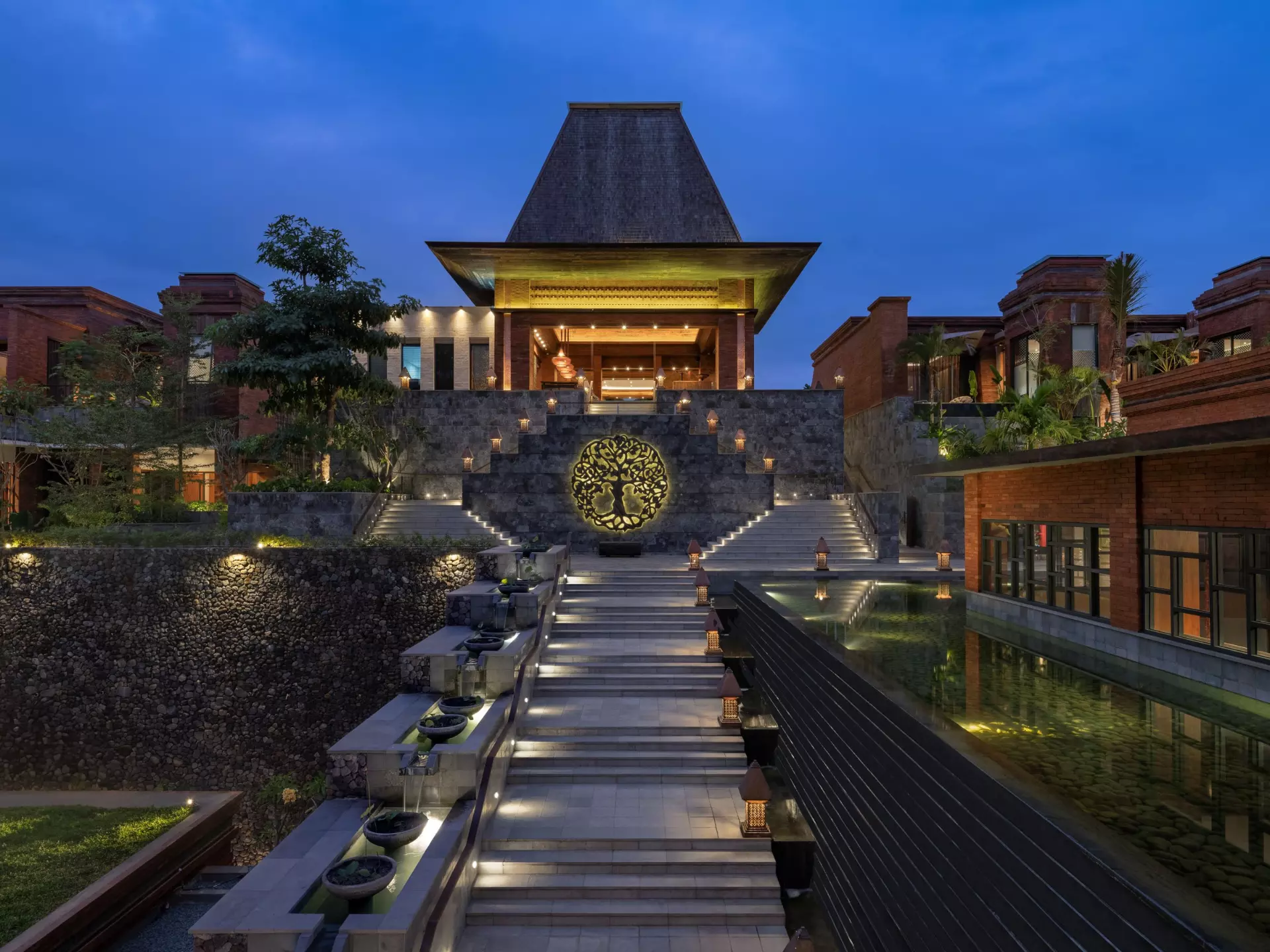 Grand stone steps leading to Garrya Bianti Yogyakarta entrance, bright lights and serene ambiance.